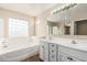 Bathroom features a double sink vanity and a soaking tub with glass block window at 18096 N Arbor Dr, Maricopa, AZ 85138