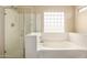 Bright bathroom featuring a glass-enclosed shower and a large soaking tub at 18096 N Arbor Dr, Maricopa, AZ 85138
