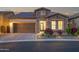Charming stone home with a well-manicured lawn, warm lighting, and a stylish garage door at dusk at 1915 N Bernard Cir, Mesa, AZ 85207