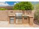 Outdoor kitchen has a built-in grill, mini-fridge, and stainless steel cabinets on a stone base at 20809 N 1St Ave, Phoenix, AZ 85027