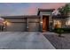 Charming exterior view showcasing a three-car garage and desert landscaping at dusk at 22166 N Lakeside Dr, Maricopa, AZ 85138