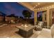Inviting outdoor patio features a fire table, seating, and string lights for a cozy evening ambiance near mature landscaping at 22166 N Lakeside Dr, Maricopa, AZ 85138