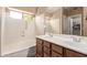 Bright bathroom featuring double sinks, a large mirror, a bathtub, and a window at 22683 N Aaron Rd, Maricopa, AZ 85138