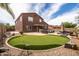 Sprawling backyard with synthetic putting green, pool, hot tub, covered bar, and desert landscaping at 3488 N Lady Lake Ln, Casa Grande, AZ 85122