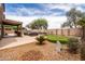 Lush backyard with covered patio, putting green, outdoor kitchen, and mature trees at 3488 N Lady Lake Ln, Casa Grande, AZ 85122