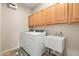 Bright laundry room with washer, dryer, wood cabinets, and utility sink at 3488 N Lady Lake Ln, Casa Grande, AZ 85122