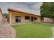 Backyard view featuring a covered patio, artificial turf, and mature tree at 4017 W Irma Ln, Glendale, AZ 85308
