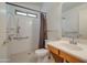 White bathroom with shower featuring a grab bar and built-in seat, and a single sink vanity at 4017 W Irma Ln, Glendale, AZ 85308