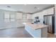 Bright open kitchen featuring a large island, white cabinetry, stainless steel appliances, and wood flooring at 4467 S 116Th Ln, Avondale, AZ 85323