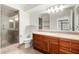 Bathroom featuring walk-in shower, toilet, wood cabinets, and large mirror at 4808 N 24Th St # 231, Phoenix, AZ 85016
