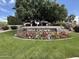 View of the community entrance sign with mature trees and flowers at 4944 E Villa Theresa Dr, Scottsdale, AZ 85254