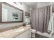 Bathroom featuring a vanity with granite top, decorative mirror and shower with gray curtain at 4953 W Acoma Dr, Glendale, AZ 85306