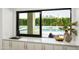 View from kitchen over looking a backyard with pool, green landscaping and water features through a black framed window at 6614 E North Ln, Paradise Valley, AZ 85253