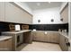Well-organized laundry room featuring black tile backsplash, light wood cabinets, and modern decor at 6614 E North Ln, Paradise Valley, AZ 85253