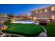 A manicured backyard with a putting green, pool with water features, and comfortable lounge area at 6621 S Balboa Dr, Gilbert, AZ 85298