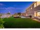 Spacious backyard featuring green lawn, pool, lounge area, and patio dining at dusk at 6621 S Balboa Dr, Gilbert, AZ 85298