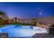A backyard pool featuring water fountains surrounded by palm trees and an outdoor sofa area at dusk at 6621 S Balboa Dr, Gilbert, AZ 85298