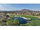 Aerial view of a lush golf course with a scenic pond and mountain backdrop at 6623 S Classic Way, Gilbert, AZ 85298