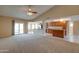 Spacious living room with carpet flooring, a ceiling fan, and sliding door access to the backyard at 7402 W Corrine Dr, Peoria, AZ 85381