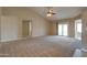Large living room with carpet, a ceiling fan, and sliding glass doors to the backyard at 7402 W Corrine Dr, Peoria, AZ 85381