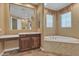 Bathroom featuring wood cabinets, vanity area, soaking tub, and custom tile accents at 844 E County Down Dr, Chandler, AZ 85249