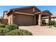 Front exterior featuring a two-car garage, covered porch with stone accents, and well-maintained landscaping at 10307 E Tiburon Ave, Mesa, AZ 85212