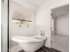 Bright bathroom with a claw foot tub, arched window and black wood-look floor at 10358 N 78Th Ave, Peoria, AZ 85345
