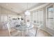 Bright dining area features a glass-top table, white chairs and cabinetry, next to a kitchen with bar seating at 10613 E Nacoma Dr, Sun Lakes, AZ 85248
