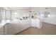 Bright, white kitchen opens to the living room, featuring tiled floors, lots of cabinetry, and windows at 10613 E Nacoma Dr, Sun Lakes, AZ 85248