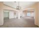 Open-concept living room featuring plush carpeting, neutral walls, and decorative hanging light fixture at 10613 E Nacoma Dr, Sun Lakes, AZ 85248