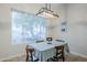 Cozy dining room featuring a table with chairs, a stylish light fixture, and a large window at 1216 E Rowlands Ln, Phoenix, AZ 85022