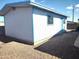 Side view of white and light blue outbuilding with secure windows and a low profile in a sunny gravel yard at 127 S 75Th Pl, Mesa, AZ 85208
