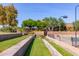 Community common area featuring lush landscaping, retaining walls, and nearby tennis courts at 12798 W Dove Wing Way, Peoria, AZ 85383