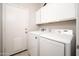 Laundry room with white cabinets, washer and dryer, and a door at 12936 W Flower St, Avondale, AZ 85392