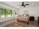 Bright bedroom featuring a ceiling fan, large window overlooking the landscaped yard, and warm neutral tones at 13023 W Tangelo Dr, Sun City West, AZ 85375