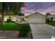 Charming single-story home featuring a two-car garage, well-maintained lawn, and desert landscaping under a vibrant sunset at 13023 W Tangelo Dr, Sun City West, AZ 85375