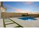 Beautiful pool with travertine deck and artificial grass accents, perfect for entertaining at 16566 W Saguaro Park Ln, Surprise, AZ 85387