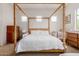 Light-filled bedroom with unique wooden canopy bed, neutral decor, and cozy seating area for relaxation at 18422 W Clinton St, Surprise, AZ 85388