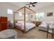 Light-filled bedroom with unique wooden canopy bed, neutral decor, and cozy seating area for relaxation at 18422 W Clinton St, Surprise, AZ 85388