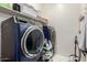 Modern laundry room features front loading washer and dryer and storage shelves at 18422 W Clinton St, Surprise, AZ 85388