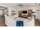 Spacious living room with modern furniture, ceiling fan, a media center, and wood flooring at 18422 W Clinton St, Surprise, AZ 85388