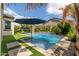 Backyard pool area with well-manicured landscaping, artificial grass, and shaded seating at 18422 W Clinton St, Surprise, AZ 85388
