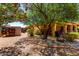 Charming backyard oasis with mature trees, rock landscaping, and cozy patio area at 2232 E Inglewood St, Mesa, AZ 85213