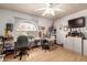 Brightly lit bedroom featuring a large window, ceiling fan, and organized storage and work areas at 2232 E Inglewood St, Mesa, AZ 85213