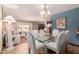 Bright dining room featuring chandelier, glass-top table with white chairs, and open access to the living room at 2232 E Inglewood St, Mesa, AZ 85213