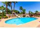 Backyard pool area complete with palms, slide, diving board, flower beds, and block wall features under a clear blue sky at 2232 E Inglewood St, Mesa, AZ 85213