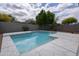 A sparkling pool is surrounded by a stone tile patio with a green privacy wall and trees in the background at 24709 N 75Th Way, Scottsdale, AZ 85255