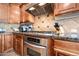 Kitchen featuring stainless steel stove, tile backsplash, range hood, and custom cabinets at 2565 N 141St Ln, Goodyear, AZ 85395