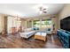 Well-lit living room boasts wood floors, a ceiling fan, and a plush sofa perfect for relaxation and entertaining at 2565 N 141St Ln, Goodyear, AZ 85395
