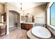 Relaxing main bathroom featuring a soaking tub, dual vanities, and tile flooring at 2565 N 141St Ln, Goodyear, AZ 85395